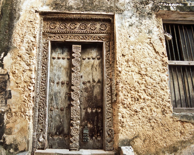 Traditionally carved Lamu door with old coral walls either side